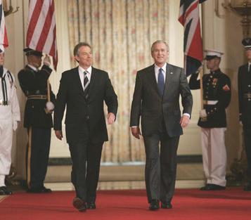 President George W. Bush traverses Cross Hall in the White House with British Prime Minister Tony Blair to attend a press conference in the East Room in 2006