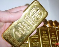 Gold bars or ingots with Krugerrands in the background.